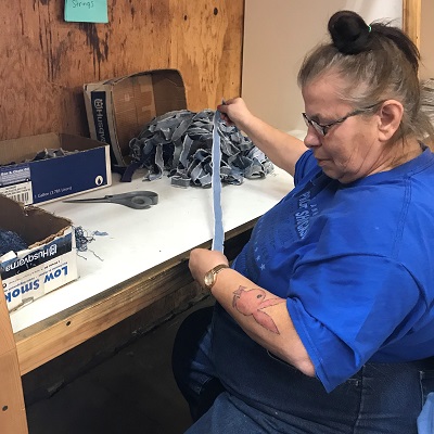 An employee sews strips of fabric together in the process of making STEP rugs.